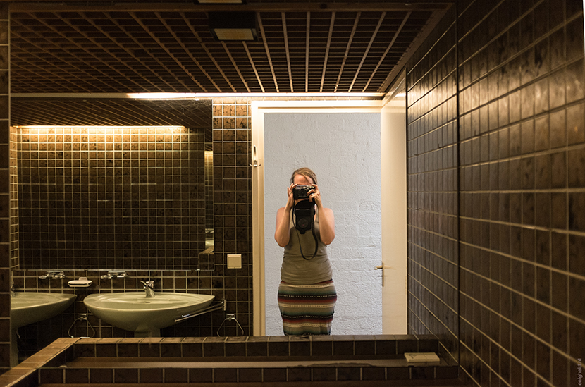 Me in the mirror of the retro bathroom with sixties / seventies vibe, in our new 60ies home. Avocado bathtub and sinks, brown tiles | house in the woods, Enigheid