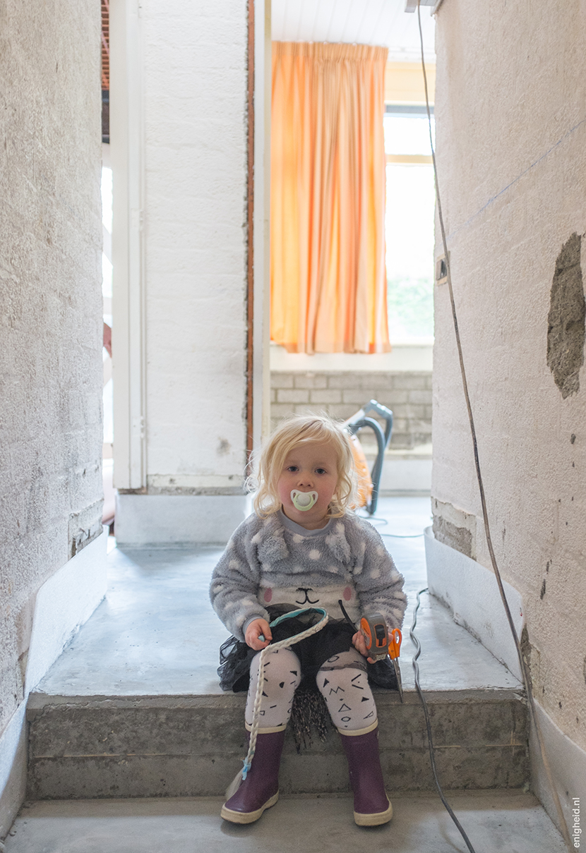 Our renovation journey is another drastic one. This is our hallway. We've installed underfloor heating and love the concrete floor on top of that! We don't have stairs anymore, only one step. Maan thinks it's a perfect seat. | Enigheid