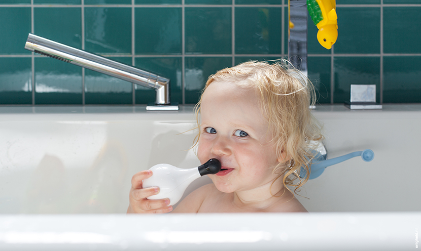 Maan in the bath tub, playing with her Moluk Design Ooginfant and Boi. Bathroom in the home of Iris Vank. Turquoise tiles and the Dornbracht Mem series faucets | Enigheid