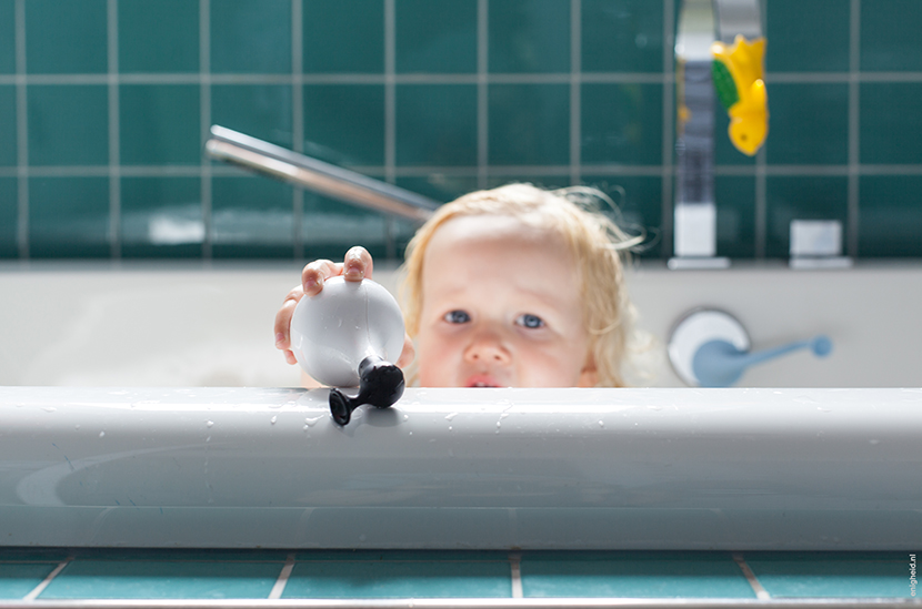 Maan in the bath tub, playing with her Moluk Design ooginfant and Boi. Bathroom in the home of Iris Vank. Turquoise tiles and the Dornbracht Mem series faucets | Enigheid