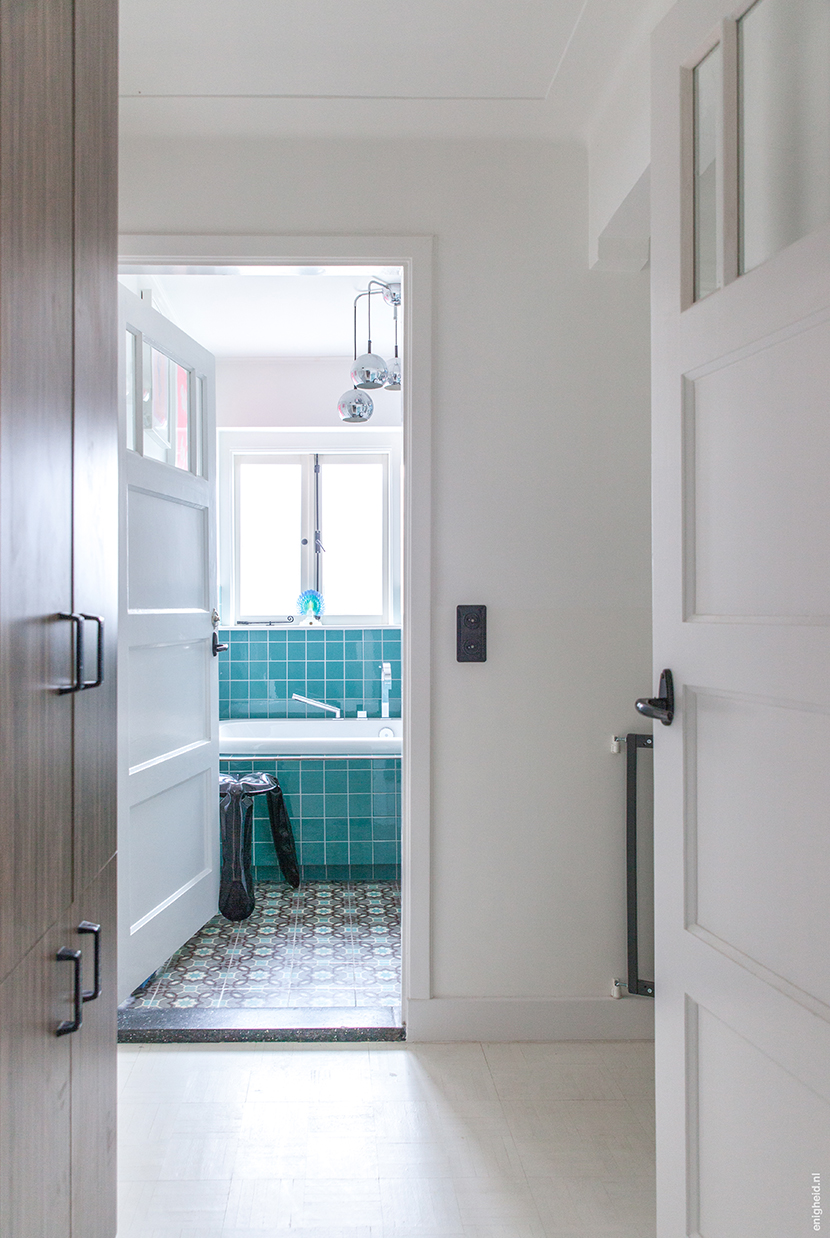 Bathrooms in the home of Iris Vank. Turquoise tiles on the wall, antique patterned tiles on the floor, plop chair by Hay and the Dornbracht Mem series faucets | Enigheid