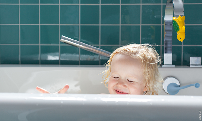 Maan in the bath tub, playing with her Moluk Design ooginfant and Boi. Bathroom in the home of Iris Vank. Turquoise tiles and the Dornbracht Mem series faucets | Enigheid