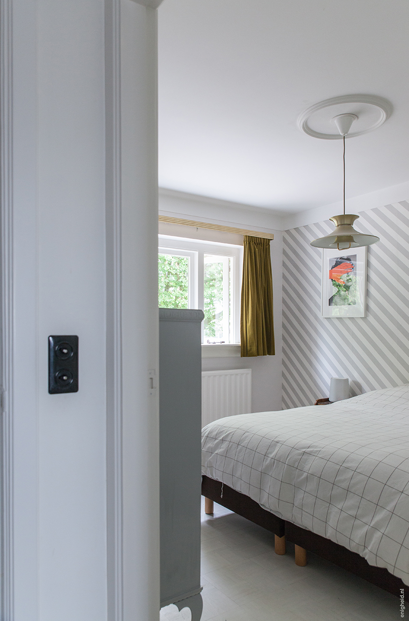 Bedroom in the home of Iris Vank, with vintage ceiling light, Hay bedding (by Scholten and Baijings), artwork by Tyler Spangler and Zilverblauw wallpaper | Enigheid